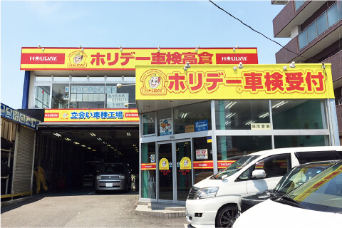 店舗外観写真:黄色の看板で、「ホリデー車検高倉」の文字が目印です。